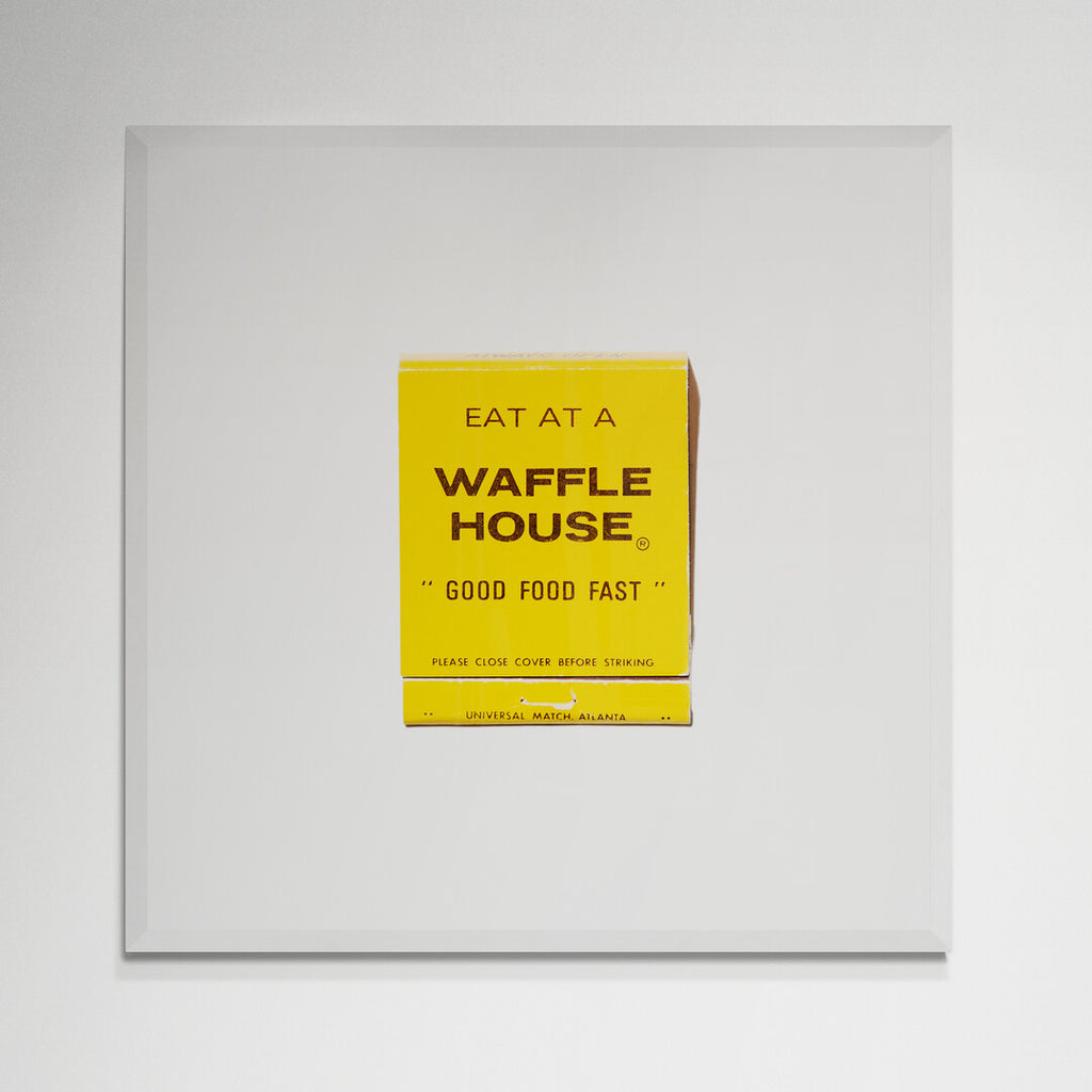 Waffle House matchbook print in white frame on kitchen wall